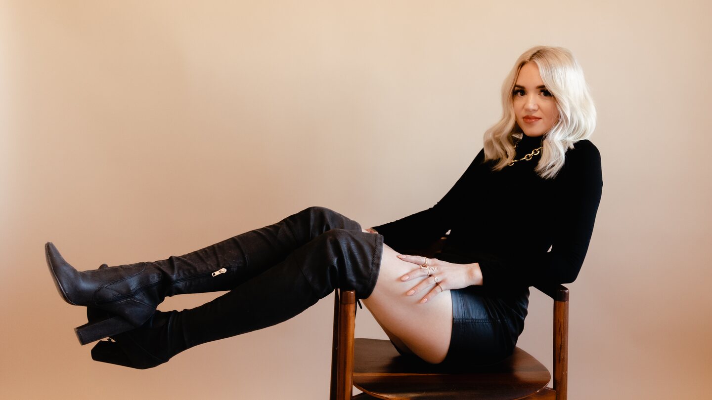 Rachel Hope seated in black against a warm neutral backdrop