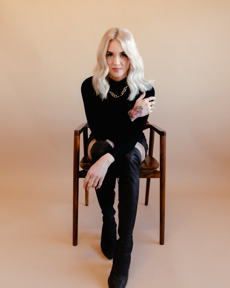 Rachel Hope seated in black against a warm neutral backdrop